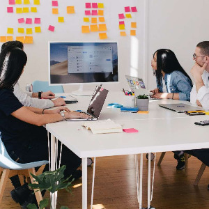 Image of people working together looking at a screen and a dashboard with notes.